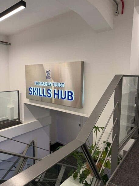 An image of the lit up CIBSE Skills Hub sign by the stairwell.